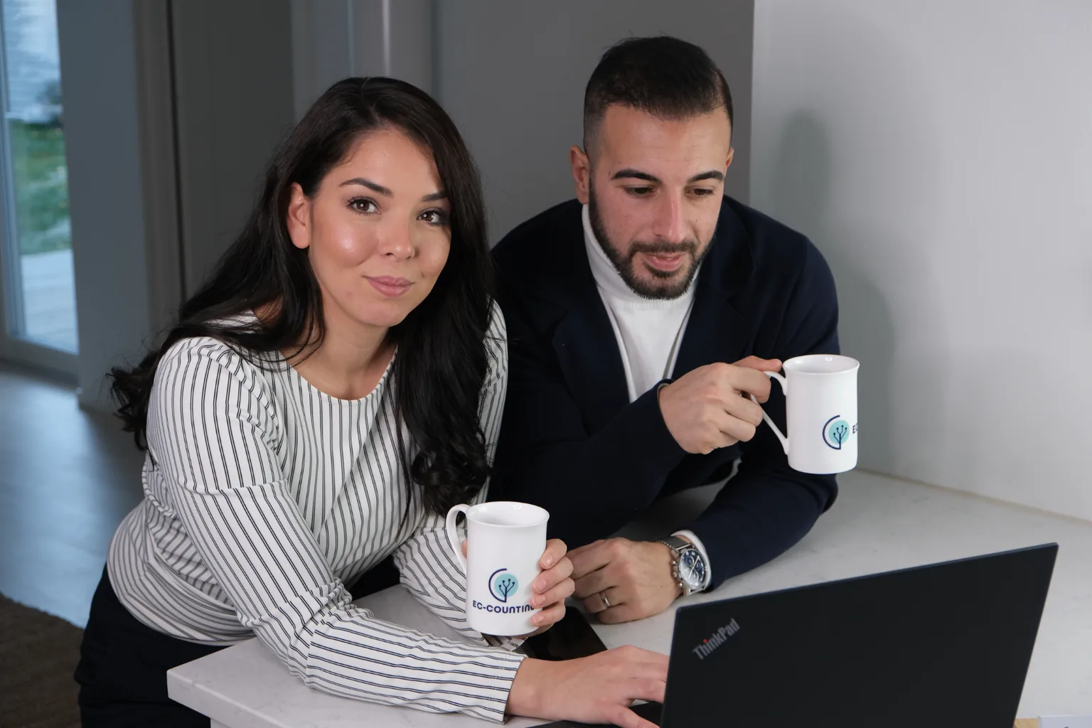 Ec-countings redovisningskonsulter vid laptop med kaffemuggar